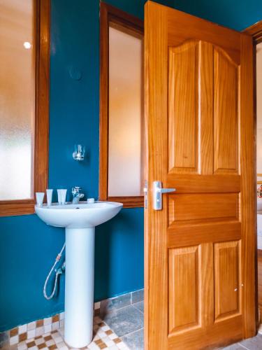 a bathroom with a sink and a wooden door at The Last Village Lodge in Athi River