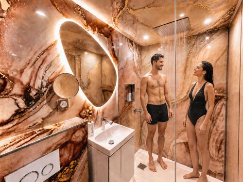 a man and a woman standing in a bathroom at MRODBNB - Escapade Romantique - Appart Neuf- 25m Plage & Resto - Ciné - Popcorn - Ciel de Pluie XXL in Cancale