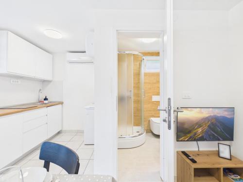 a white kitchen with a table and a bathroom at Apartments Jan in Banjole