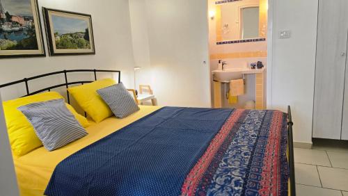 a bedroom with a bed with yellow pillows and a sink at Apartment Neno - Terrace & Parking in Veli Lošinj