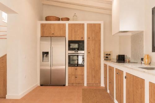 a kitchen with a stainless steel refrigerator and wooden cabinets at Finca La Oliveta Ronda in Ronda