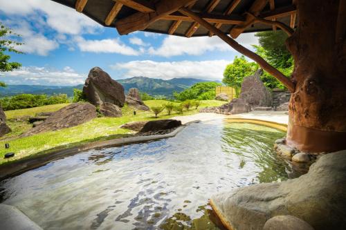 a large pool of water in a field with rocks at La Vista Minami Aso Grand opening October 2nd 2026 in Minami Aso