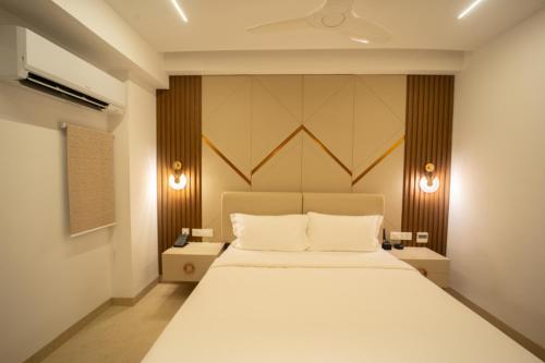 a bedroom with a large white bed with two lamps at Sawariya Hotels in Tiruvannāmalai