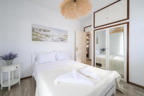 a white bedroom with a bed and a mirror at Cleopatra Residence in Perea