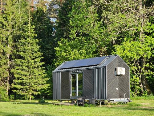 a black tiny house in a field with trees at refleXions in Kabakelis