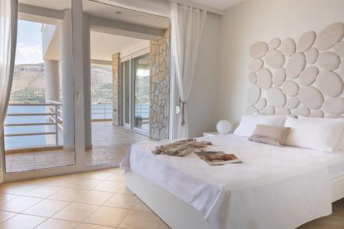 a white bedroom with a large bed and a balcony at Ionion exclusive villa in Syvota
