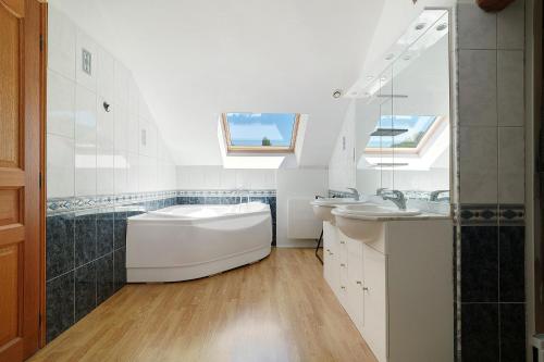 a white bathroom with two sinks and a tub at La Mailleraie - Le Moulin in Valojoulx