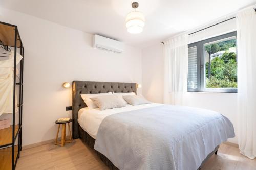 a white bedroom with a bed and a window at Azure Adriatic in Prožura