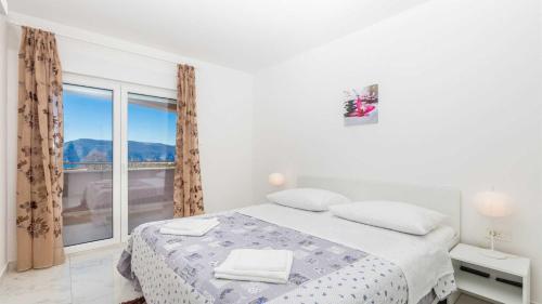 a white bedroom with a bed and a large window at Villa Isabella by Villas Guide in Malinska