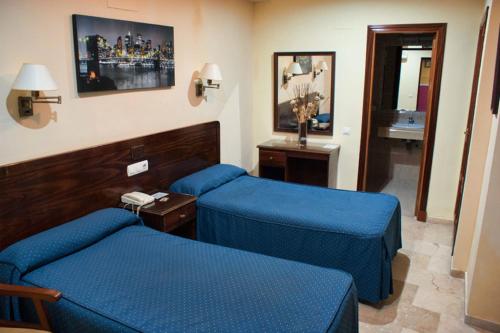 Habitación de hotel con 2 camas azules y teléfono en Hotel Nova Centro en Jerez de la Frontera
