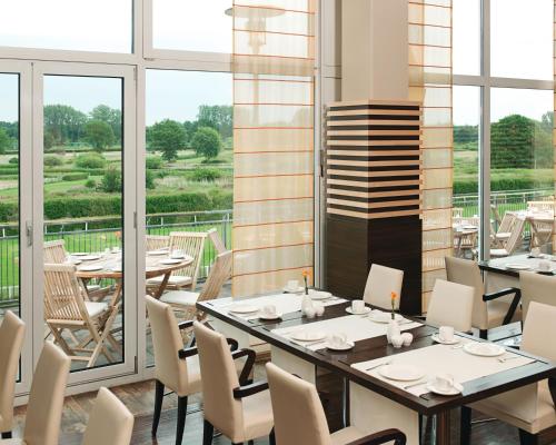 a dining room with tables and chairs and windows at PLAZA INN Hamburg Horner Rennbahn in Hamburg