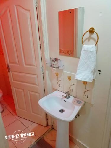 a bathroom with a white sink and a mirror at Shikaz Homes 2 Bedroom Near Jkia Airport in Nairobi
