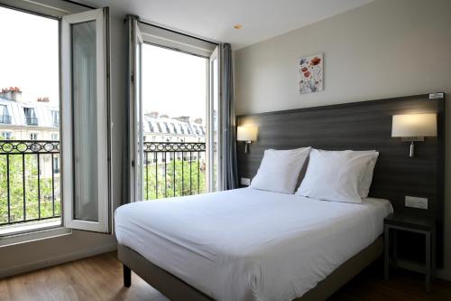 a bedroom with a large bed and two large windows at Hipotel Paris Voltaire Bastille in Paris