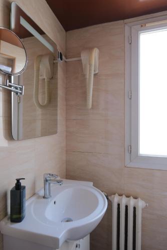 a bathroom with a white sink and a window at Hipotel Paris Voltaire Bastille in Paris