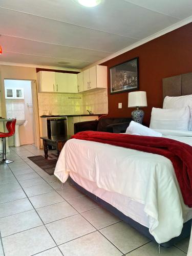 a hotel room with a large bed and a kitchen at RAMATA GUEST HOUSE in Pretoria
