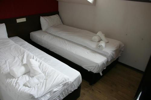 two beds in a room with white sheets and towels at Alexander 3327 in Bansko