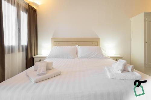 a bedroom with a white bed with two towels on it at Hotiday Punta Sardegna in Palau