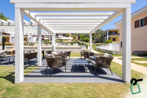 a pergola with chairs and tables on a patio at Hotiday Punta Sardegna in Palau