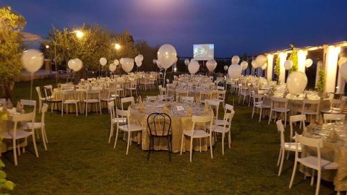 a group of tables and chairs with white tables and balloons at Tenuta Orsanese in Ginosa Marina