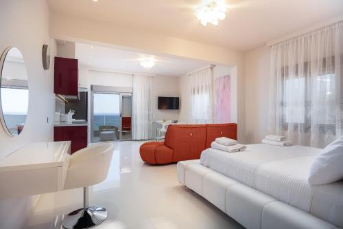 a white bedroom with a bed and a red chair at MGM Suites in Panormos Rethymno