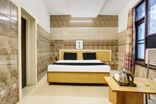 a bedroom with a bed in a room with a table at Hotel O Jammu Near Ragunath Bazaar Formerly GoodWill in Jammu