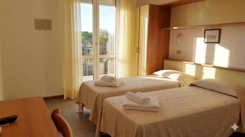 a hotel room with two beds and a window at Hotel Conti in Rimini