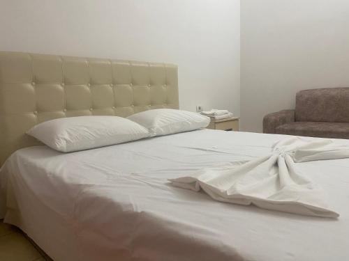 a white bed with a white blanket and a chair at Kokaj3B in Hani Hotit