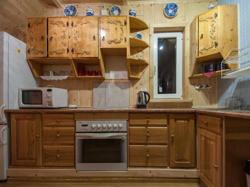 eine Küche mit Holzschränken und einem Herd mit Backofen in der Unterkunft Pokoje u Sarnowskich in Kościelisko