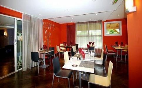 een eetkamer met rode muren en tafels en stoelen bij Kyriad Direct Lure in Lure