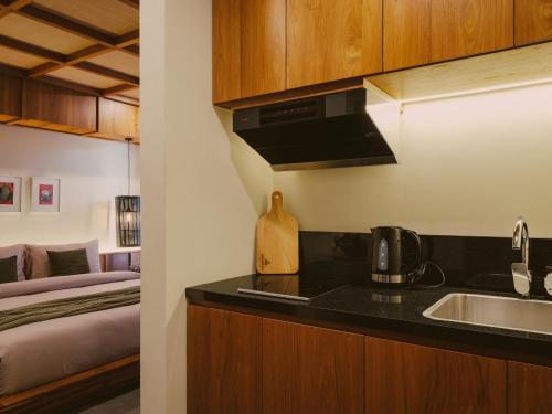 a kitchen with a sink and a bed in a room at Anandaya Sanur in Sanur