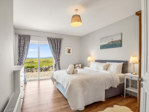a bedroom with a large bed and a window at Paddy Carrolls Cottage in Ballyconneely