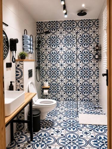 a bathroom with a toilet and a shower with blue and white tiles at Noclegi Na Końcu Świata Bielpon in Przemyśl