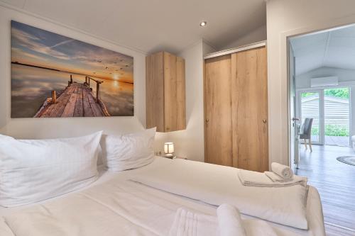 a bedroom with a white bed with a painting on the wall at Ferienhaus "Ostseeperle" mit kostenfreier Saunanutzung, Grundstück Umzäunt in Scharbeutz