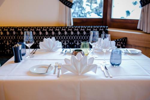 a table with a white table cloth with glasses and utensils at Hotel Piz Buin Klosters in Klosters