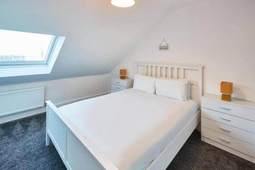 a white bedroom with a large bed and a window at Skinningrove Beach House 1 in Skinningrove