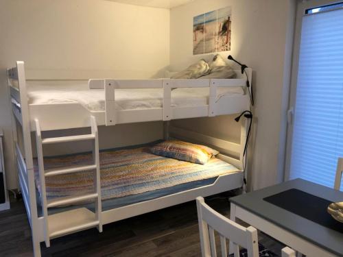 a bedroom with two bunk beds and a table at FEWO Priel Watt Nr.2 in Cuxhaven