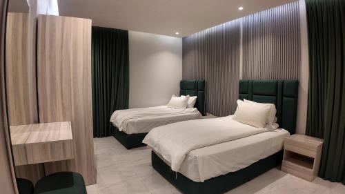 a bedroom with two beds with green headboards at أجنادين للشقق المخدومة in Riyadh