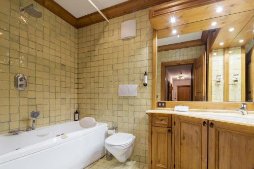 a bathroom with a tub and a toilet and a sink at Hotel Aquila in Cortina dʼAmpezzo