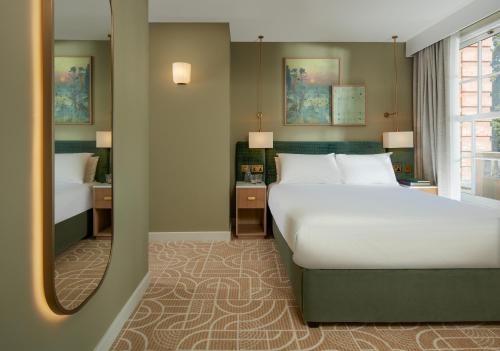 a bedroom with a large bed and a mirror at The Lensbury Resort in Richmond upon Thames