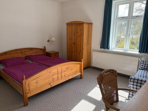 a bedroom with a wooden bed and a chair at Altes Gutshaus Schwiessel in Prebberede