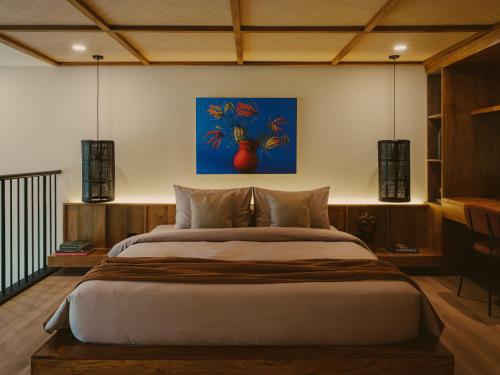a bedroom with a large bed with a blue painting on the wall at Anandaya Sanur in Sanur