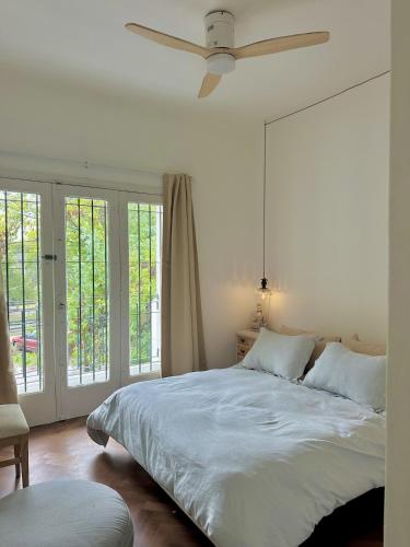 a white bedroom with a bed and a ceiling fan at Mi petit Paraiso in San Isidro