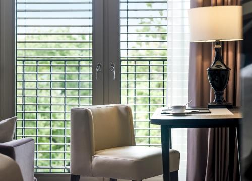 a room with a desk and a chair and a lamp at Sofitel Frankfurt Opera in Frankfurt/Main