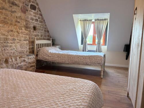 a bedroom with two beds and a brick wall at Daisy Cottage with seasonal Swimming Pool in Le Mesnil-Gilbert