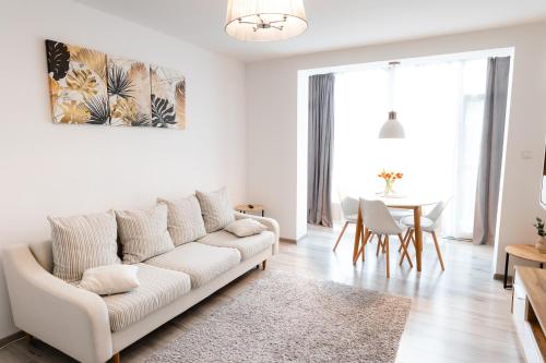 a white living room with a white couch and a table at Alexa Apartament in Târgu-Mureş