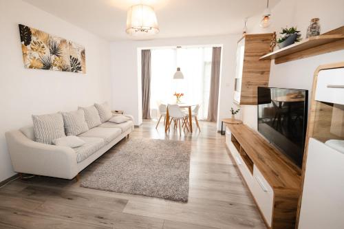 a living room with a white couch and a tv at Alexa Apartament in Târgu-Mureş