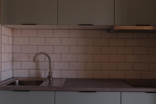 a kitchen with a sink and white tiled wall at Gaia River View in Vila Nova de Gaia