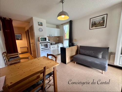 a kitchen and living room with a table and a couch at Lioran - Le bonheur de Loustal in Laveissière