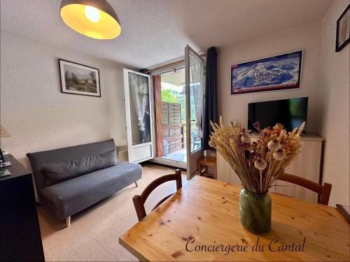 a living room with a table and a couch at Lioran - Le bonheur de Loustal in Laveissière