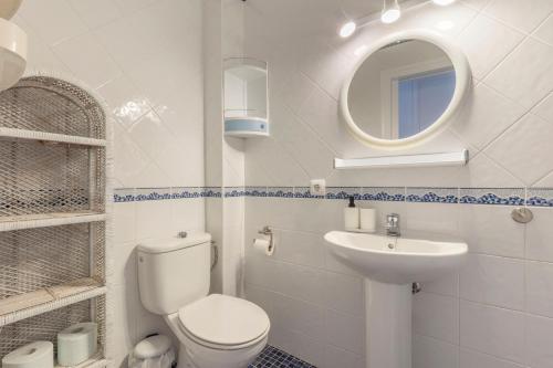 a white bathroom with a toilet and a sink at Calma Menorca in Arenal d'en Castell